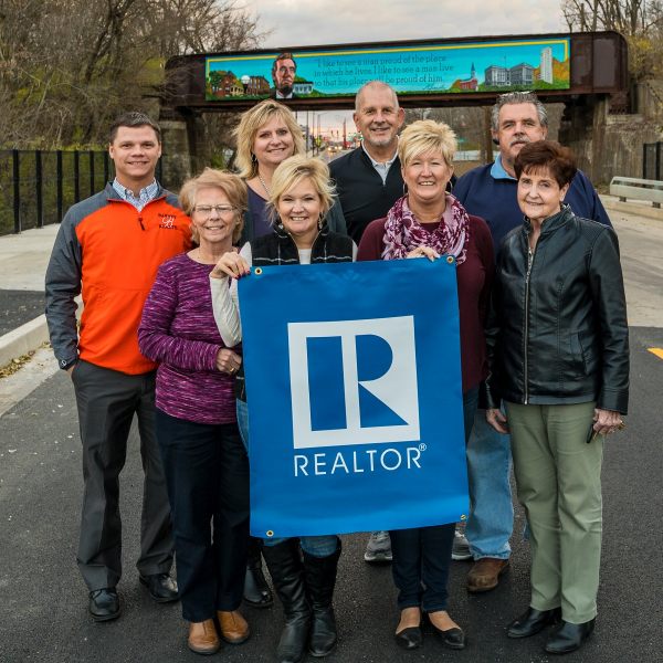 Danville Area REALTORS standing in front of Lincoln Fairchild Mural which is mounted on overpass: front row left to right Glenda Keitzmann, April Hix, Heather Cunningham and Millie Wilson; Back row left to right David Barney, Andrea Calamari, Bill Jenkins and Mike Van De Walker.
