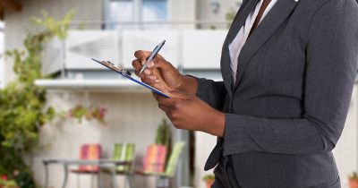 Photo of hands holding clipboard and writing on paper