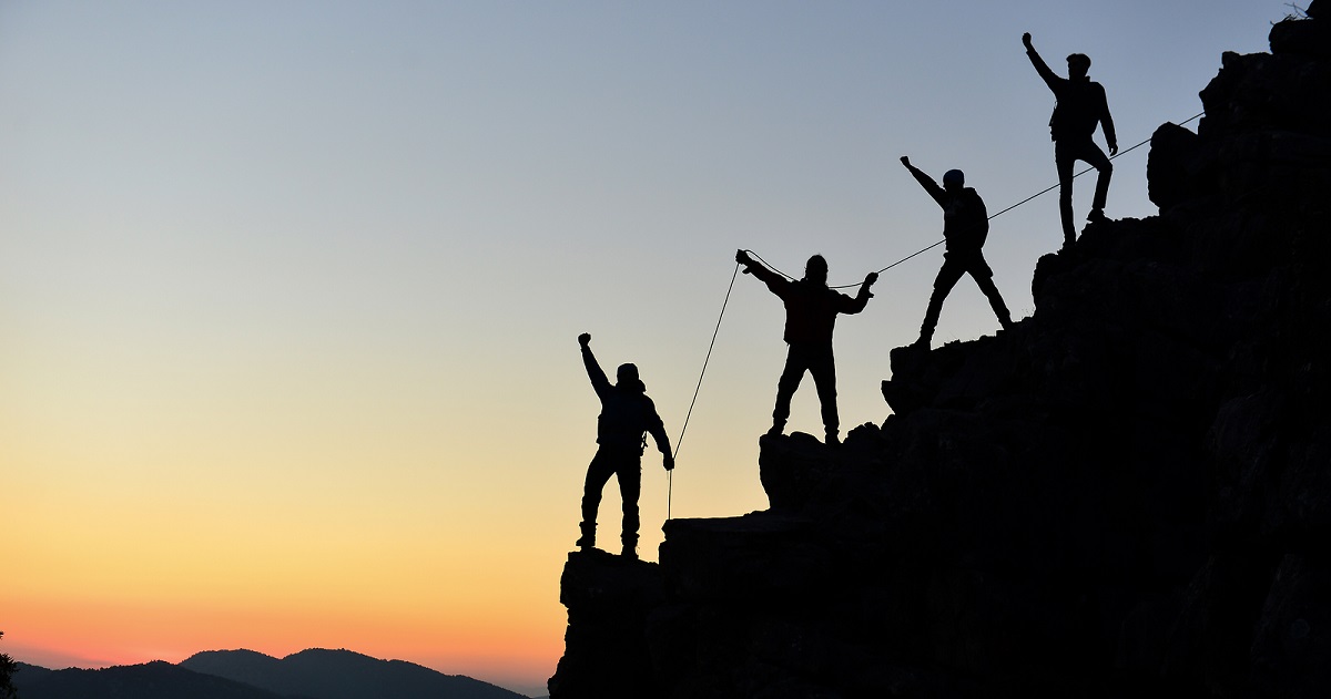 Silhouettes of four mountain climbers