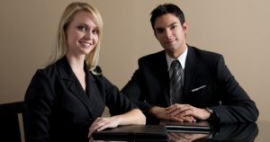 Photo of young professional woman and man sitting at a conference table.