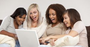 Four young women looking at something surprising and funny on their laptop