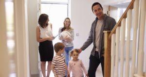 Young family and realtor viewing inside of home for sale