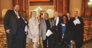 Sullivan and Illinois REALTORS® CEO Gary Clayton (fourth from right) pose with REALTORS® at “the rail” outside the House and Senate chambers in the Illinois State Capitol.